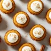 Mini Tres Leches Cakes arranged on white marble - 12 golden sponge cakes soaked in three milks, topped with whipped cream and cinnamon dust