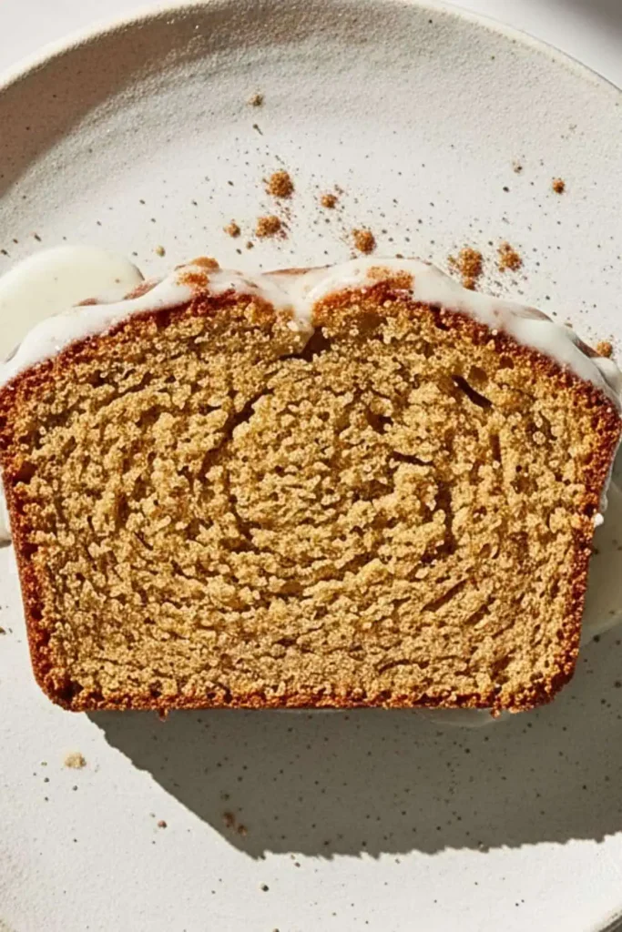 A Single Slice of Vegan Chai Spiced Loaf Cake on a rustic white dessert plate
