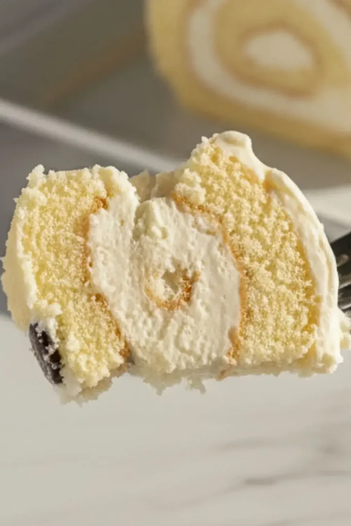 A Halloween Ghost Swiss Roll with one slice on a fork in mid-air