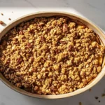 A dairy-free apple crisp in a rustic ceramic baking dish